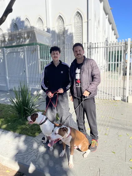 Dois homens com cães na guia em frente a uma igreja