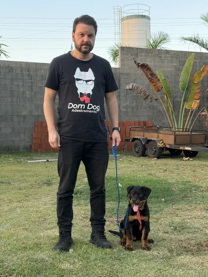 Adestrador da DomDog com um cão sentado no gramado
